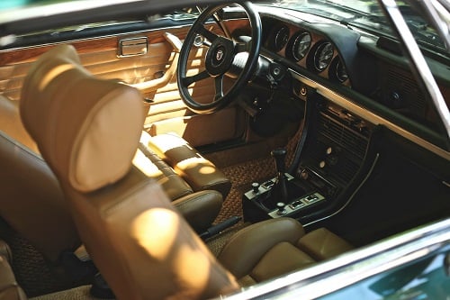 Interior of a car showing the dashboard, steering wheel, and front seats in a classic vehicle design